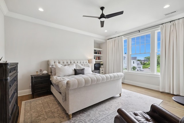 bedroom with ornamental molding, ceiling fan, and light hardwood / wood-style floors