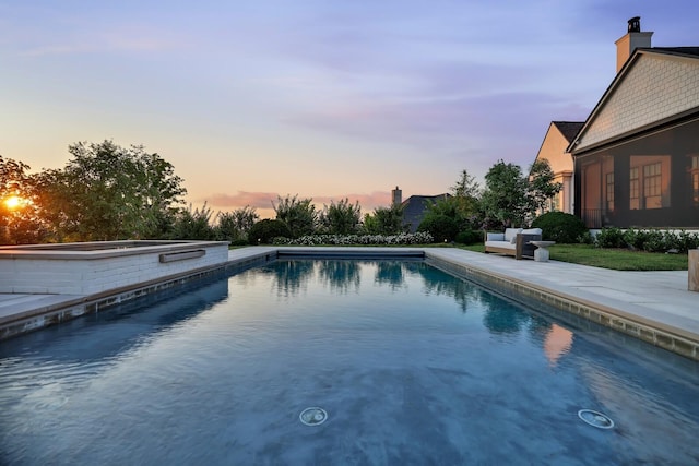 pool at dusk with a patio area