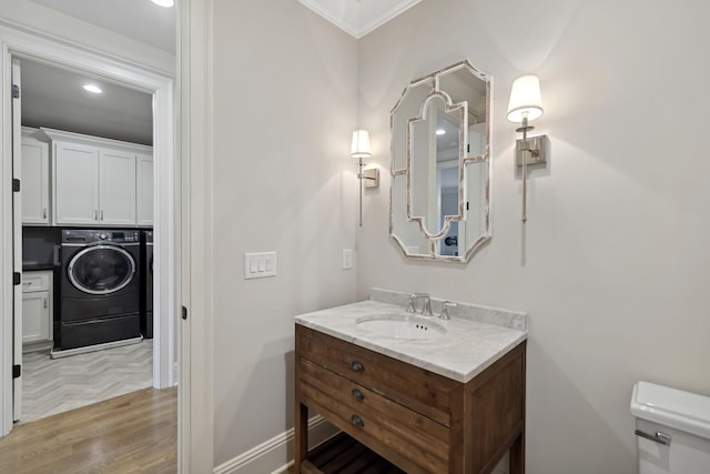 bathroom featuring washing machine and clothes dryer, ornamental molding, toilet, and vanity