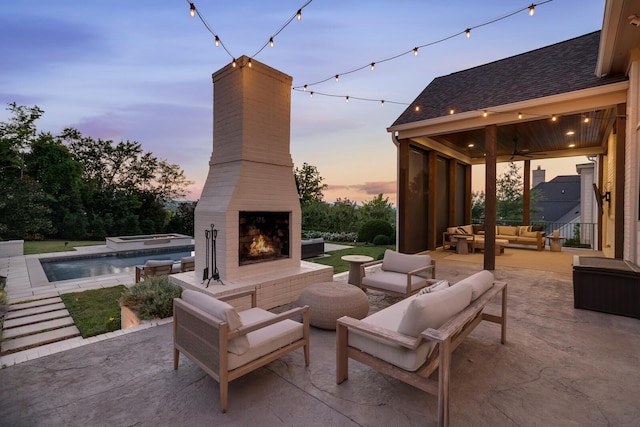 patio terrace at dusk with an outdoor living space with a fireplace