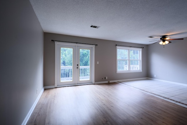 unfurnished room with ceiling fan, light hardwood / wood-style flooring, a textured ceiling, and french doors