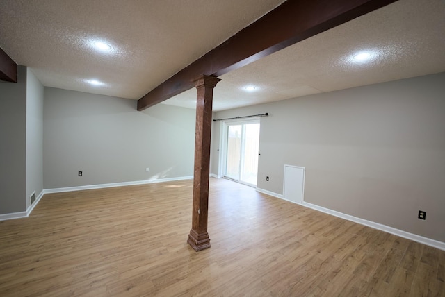 basement featuring a textured ceiling and light hardwood / wood-style floors