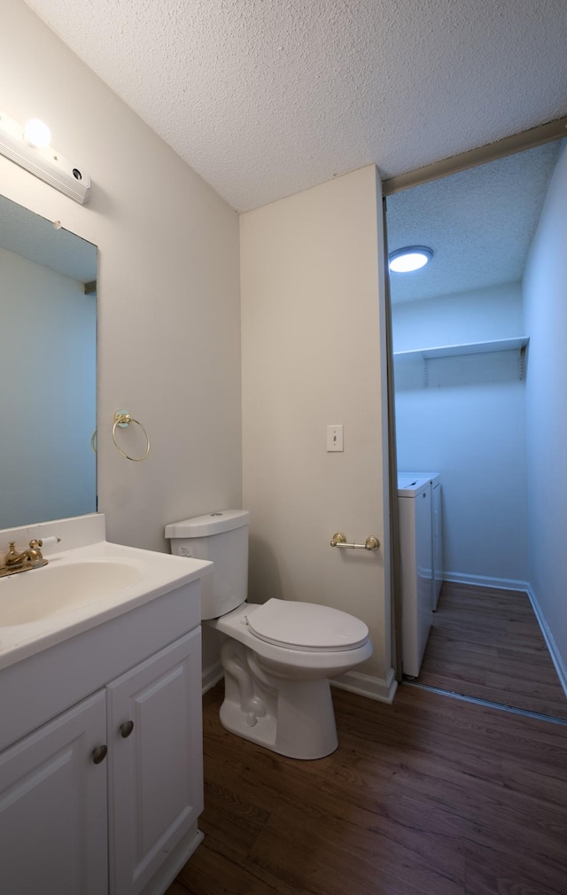 bathroom with vanity, separate washer and dryer, hardwood / wood-style floors, and a textured ceiling