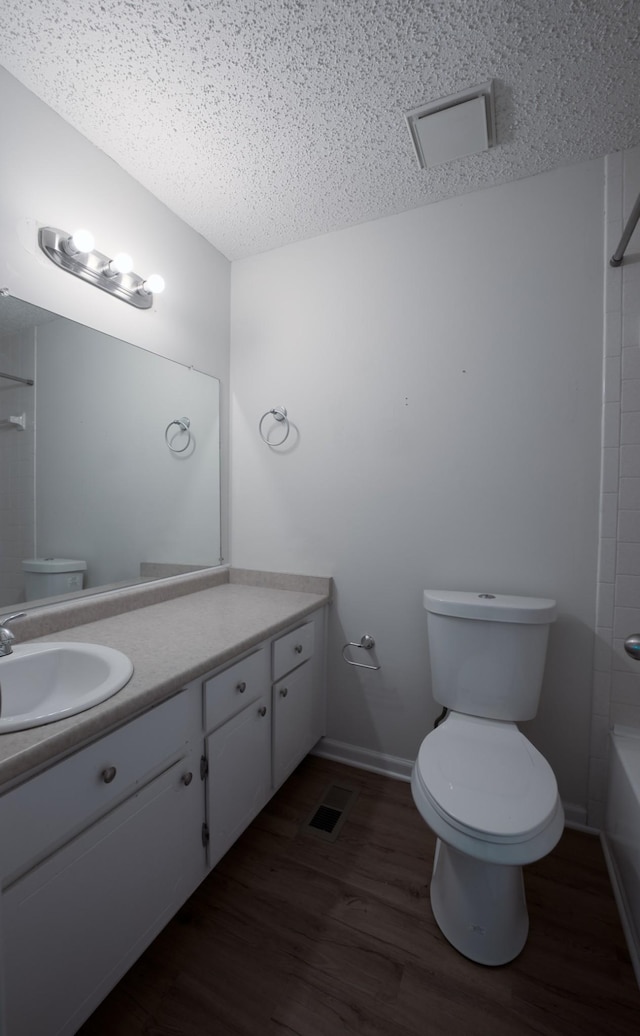 full bathroom with toilet, a textured ceiling, vanity, shower / washtub combination, and hardwood / wood-style flooring