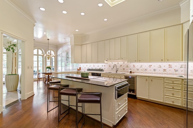 kitchen featuring a center island, crown molding, sink, a breakfast bar area, and beverage cooler