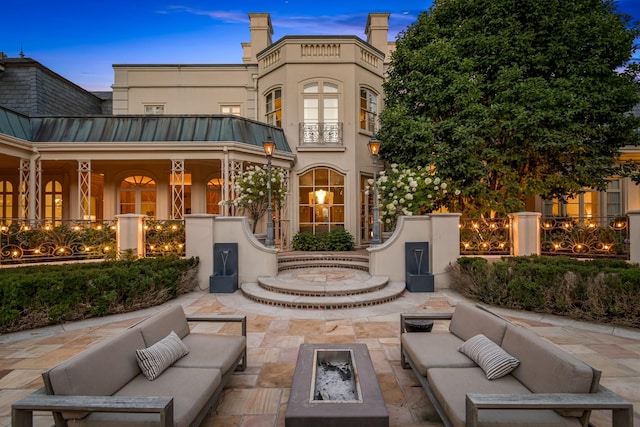 back house at dusk with a patio and an outdoor living space with a fire pit