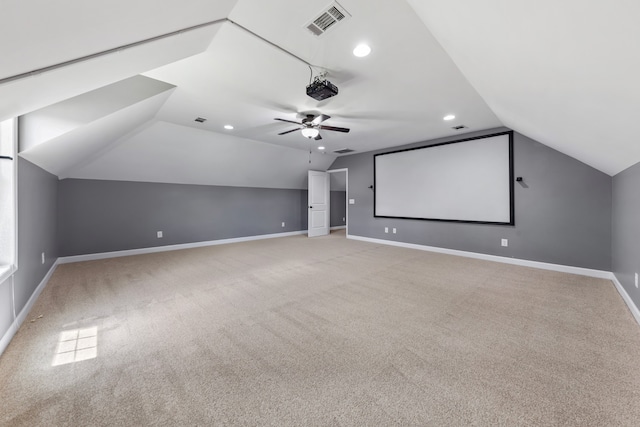 carpeted home theater room with ceiling fan and vaulted ceiling