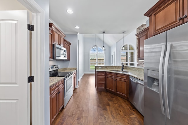 kitchen with light stone counters, dark hardwood / wood-style floors, appliances with stainless steel finishes, decorative light fixtures, and sink