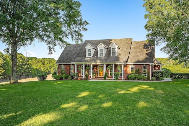 new england style home with brick siding, a porch, and a front yard