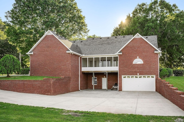 view of front of property with a garage, brick siding, a shingled roof, a sunroom, and driveway