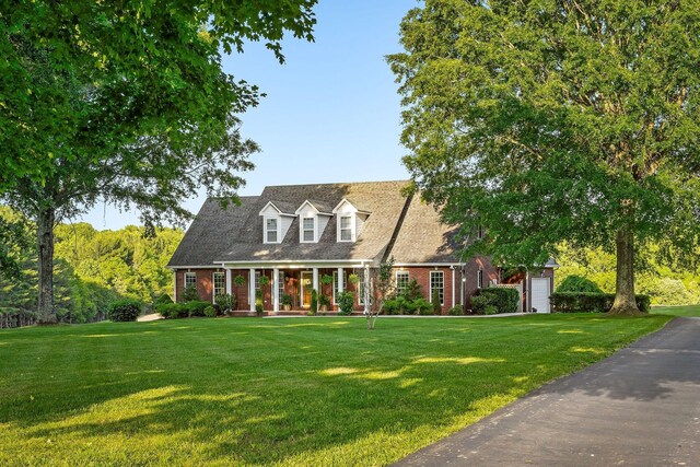 cape cod-style house featuring a garage and a front yard