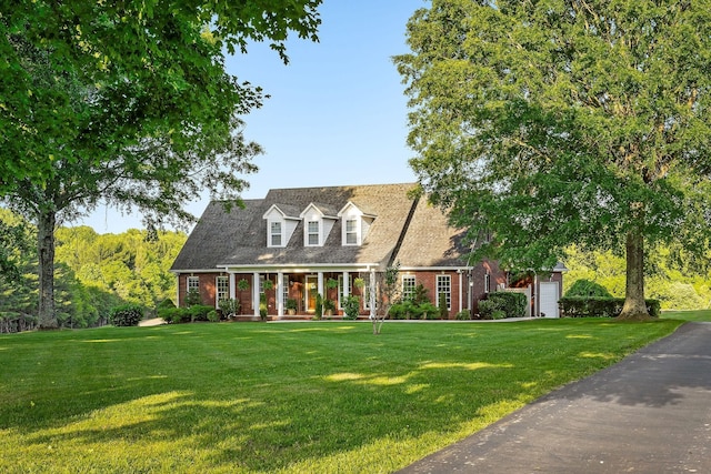 cape cod home with brick siding, a porch, and a front yard