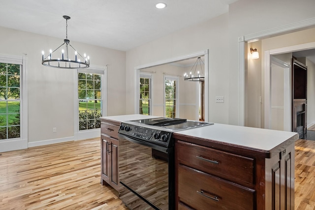 kitchen featuring a chandelier, light wood-style floors, light countertops, a center island, and black electric range oven