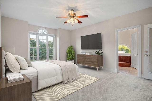 bedroom featuring light colored carpet, multiple windows, ensuite bath, and baseboards