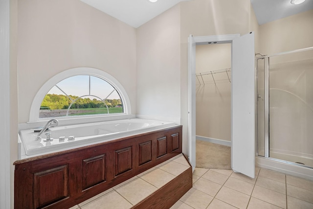 bathroom featuring tile patterned flooring, a spacious closet, a bath, and a shower stall