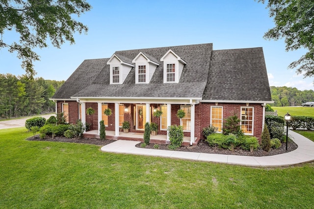 cape cod house featuring covered porch, a shingled roof, a front lawn, and brick siding