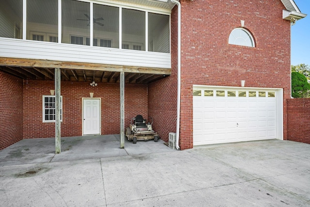 exterior space featuring a garage, concrete driveway, brick siding, and a sunroom