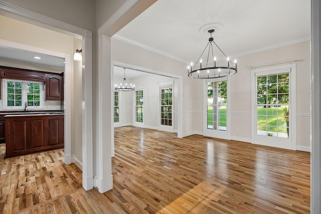 unfurnished dining area featuring an inviting chandelier, light wood-style flooring, and ornamental molding