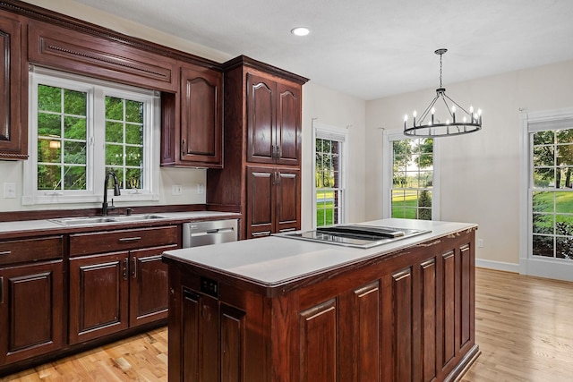 kitchen featuring light wood finished floors, a kitchen island, hanging light fixtures, stovetop, and a sink