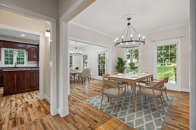 dining area featuring ornamental molding, light wood finished floors, plenty of natural light, and a notable chandelier