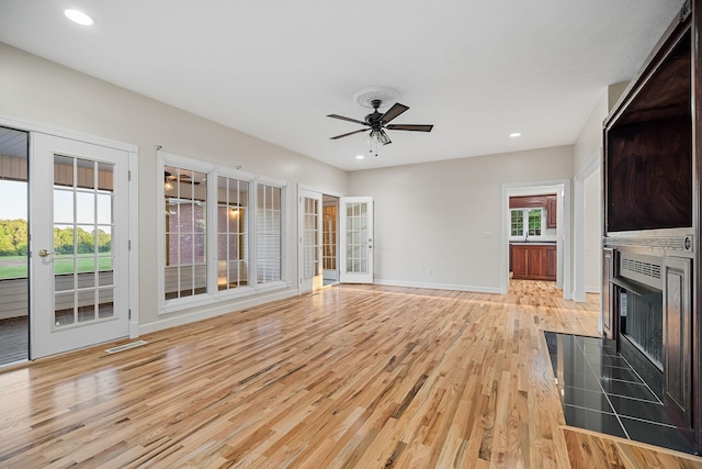 unfurnished living room with light wood finished floors, baseboards, a ceiling fan, a fireplace with flush hearth, and recessed lighting