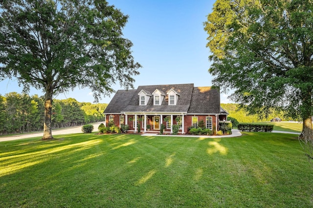 cape cod home featuring covered porch, a front lawn, and brick siding