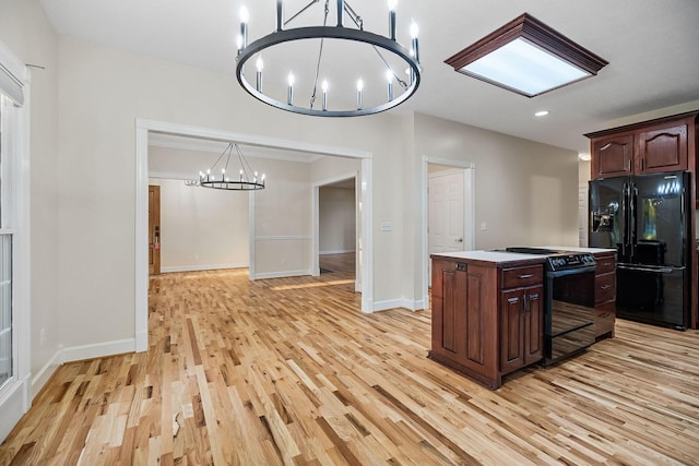 kitchen featuring a kitchen island, an inviting chandelier, light countertops, black appliances, and pendant lighting