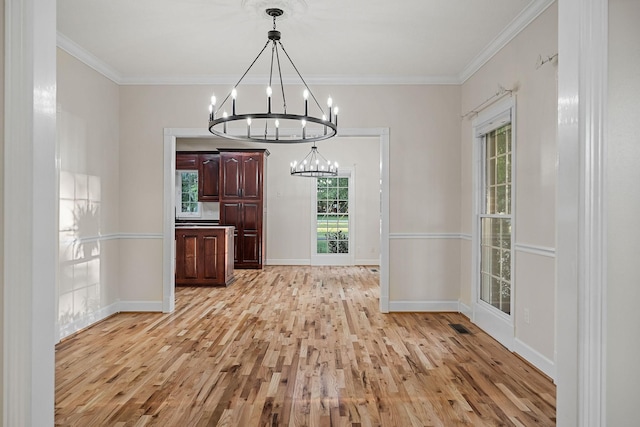 unfurnished dining area with light wood finished floors, baseboards, ornamental molding, and a chandelier