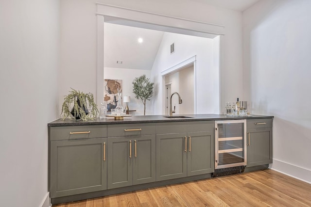 bar featuring vaulted ceiling, sink, wine cooler, and light hardwood / wood-style floors