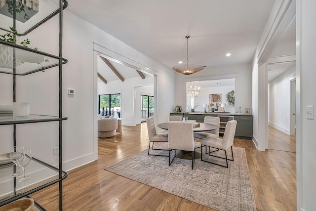 dining area with vaulted ceiling with beams, light hardwood / wood-style floors, and a notable chandelier