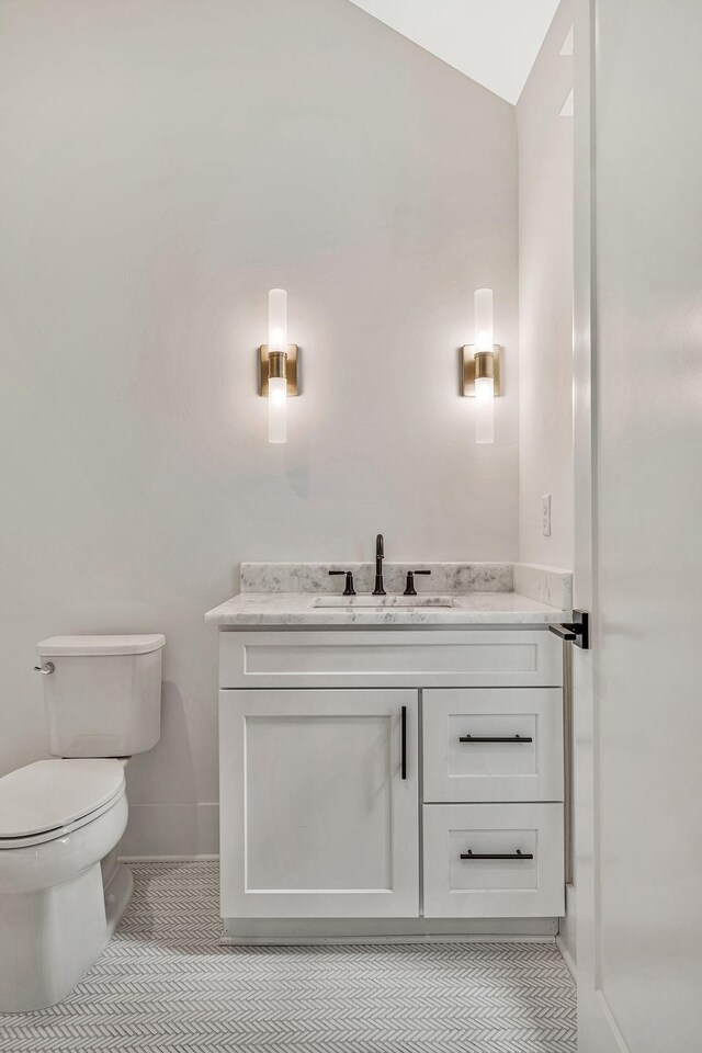 bathroom featuring lofted ceiling, vanity, toilet, and tile patterned flooring