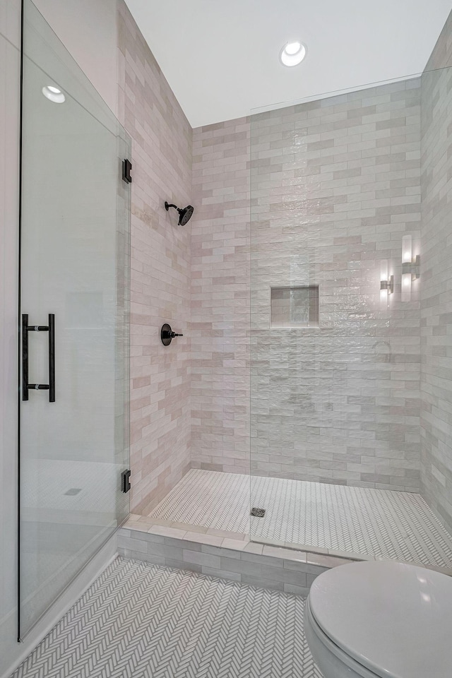 bathroom with tile patterned flooring, an enclosed shower, and toilet