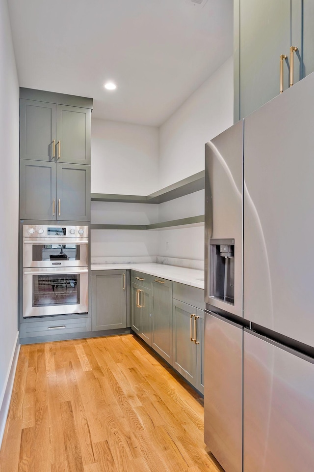 kitchen with appliances with stainless steel finishes and light hardwood / wood-style floors