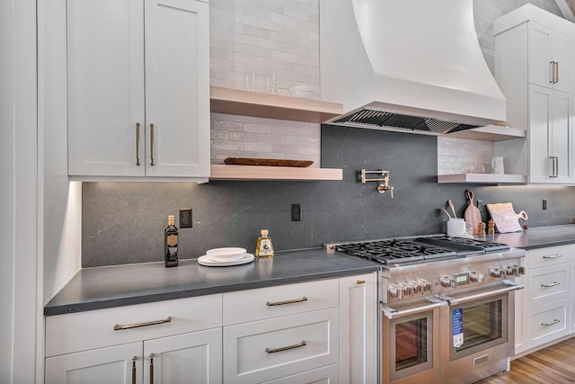 kitchen featuring premium range hood, double oven range, backsplash, and white cabinets