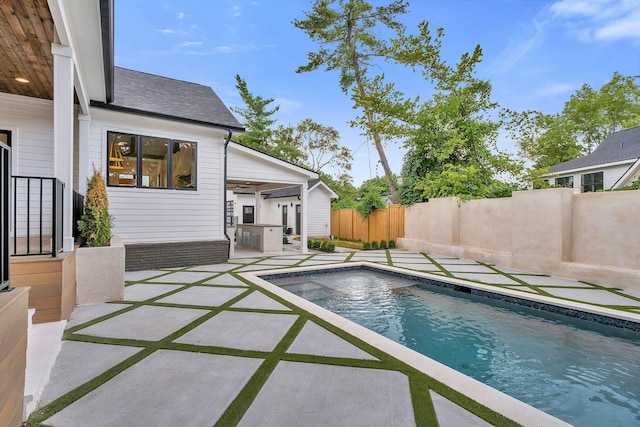 view of swimming pool with an outdoor kitchen and a patio area