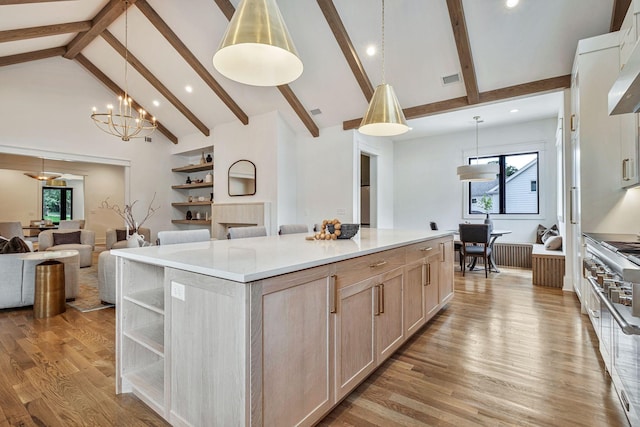 kitchen with hanging light fixtures, high vaulted ceiling, a spacious island, light brown cabinets, and light wood-type flooring