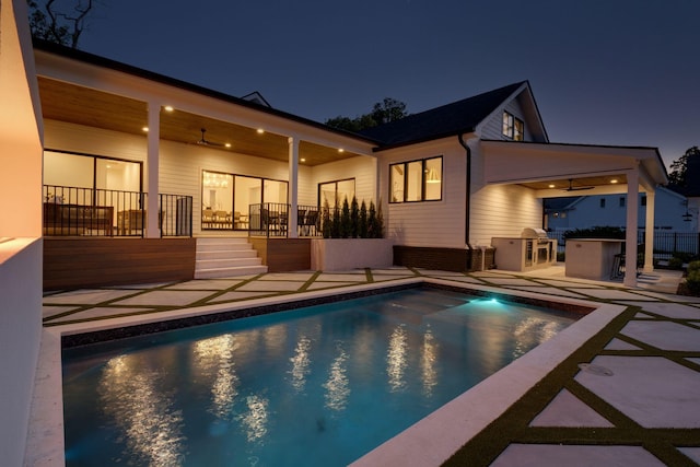 pool at twilight with exterior kitchen and a patio