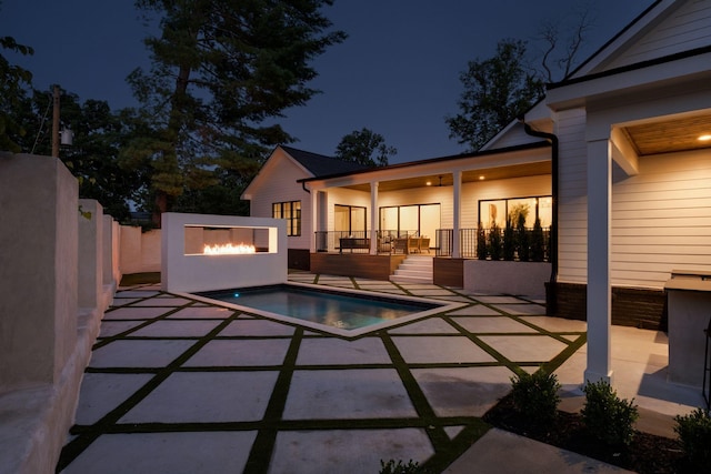 pool at night featuring a patio area