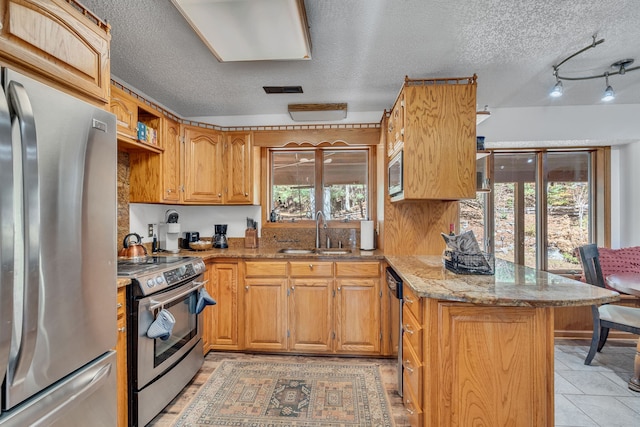 kitchen with plenty of natural light, sink, stainless steel appliances, and light tile patterned floors