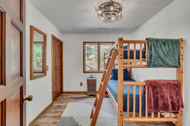 bedroom with a textured ceiling and light hardwood / wood-style floors