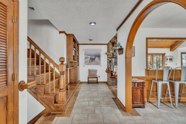 entrance foyer with beamed ceiling, a textured ceiling, and light tile patterned floors