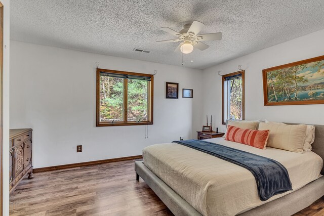 bedroom featuring wood-type flooring, a textured ceiling, and ceiling fan