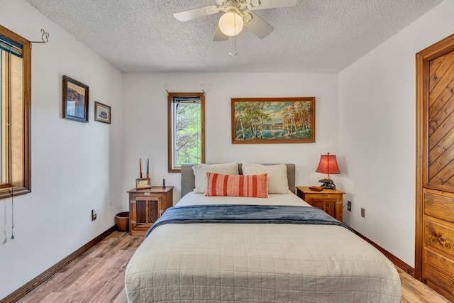 bedroom with ceiling fan, light wood-type flooring, and a textured ceiling