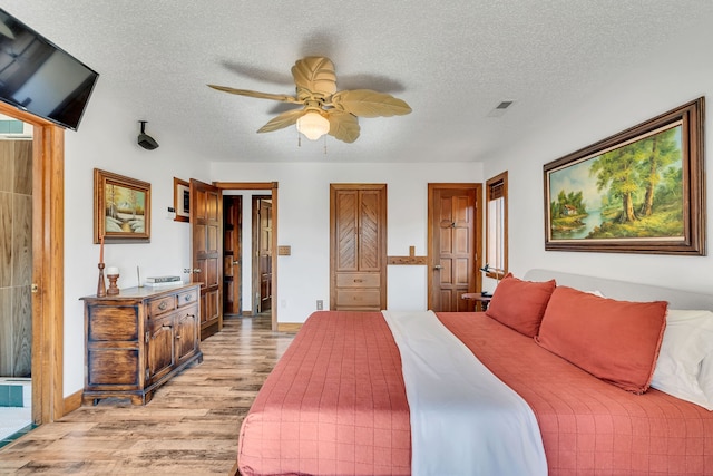 bedroom with light hardwood / wood-style floors, a textured ceiling, and ceiling fan