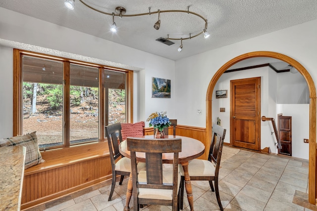 dining space with light tile patterned flooring, a textured ceiling, and rail lighting