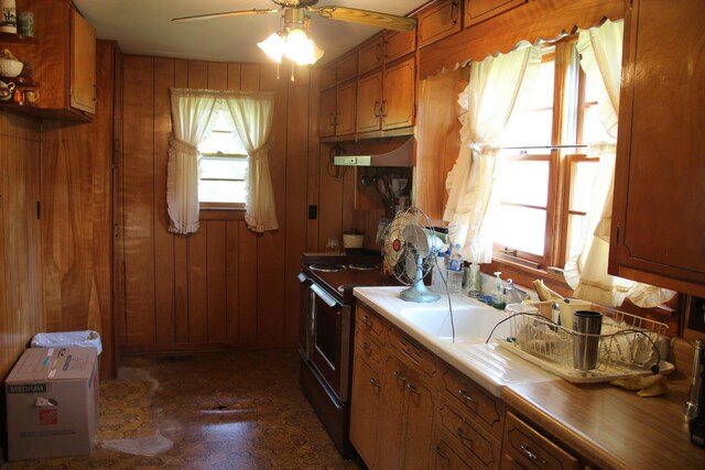 kitchen featuring ceiling fan, wood walls, and electric range