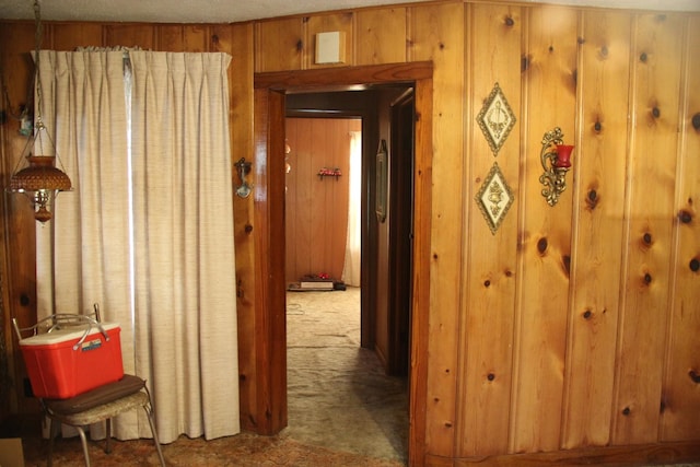 hallway with dark colored carpet and wood walls