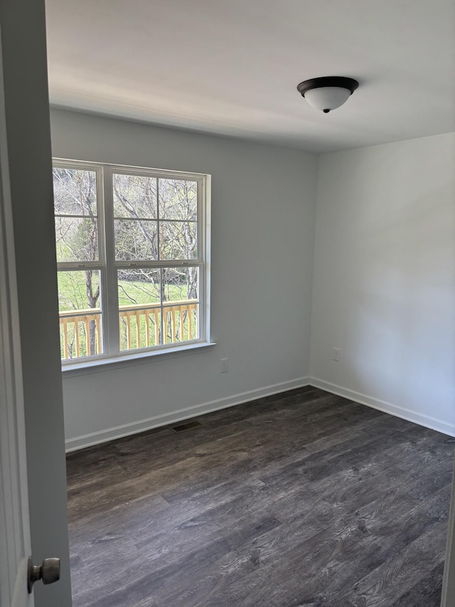 unfurnished room featuring dark wood-type flooring, baseboards, and visible vents