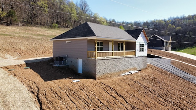 view of side of property featuring a porch, a shingled roof, and cooling unit