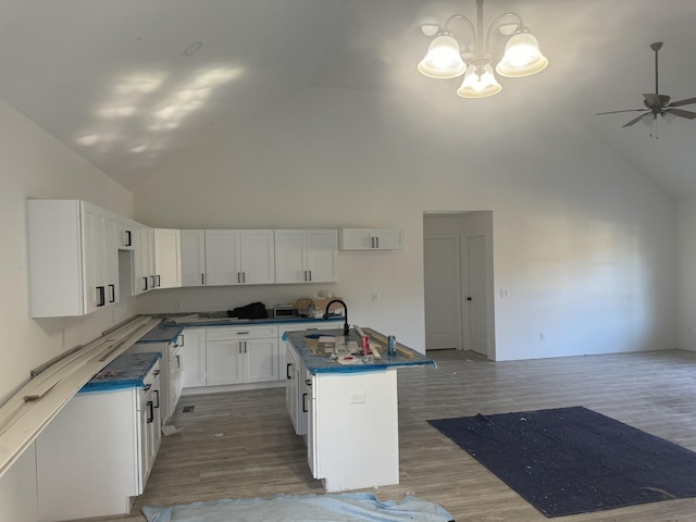 kitchen featuring high vaulted ceiling, a center island with sink, ceiling fan with notable chandelier, dark hardwood / wood-style flooring, and white cabinetry